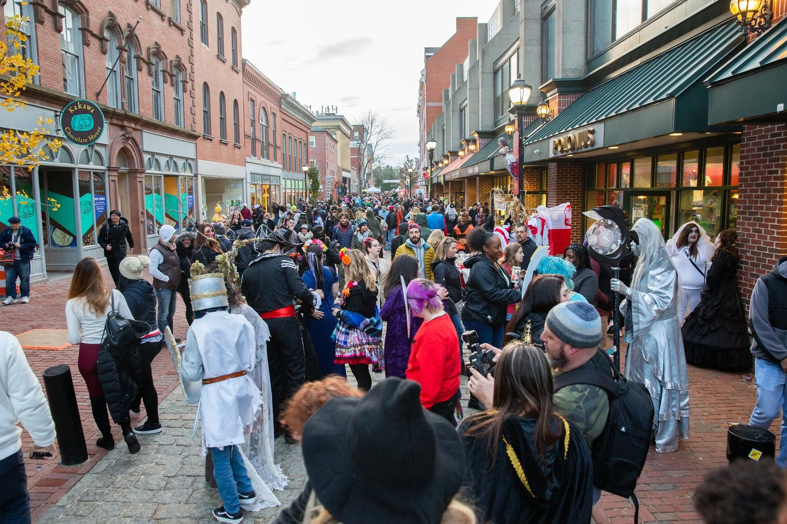 Visitors in Halloween costumes fill a downtown Salem pedestrian shopping street.